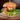 Gourmet burger with fresh lettuce, juicy tomato, crispy bacon, and melted cheese at Playa Manglares' restaurant on Isla de Barú. This delicious meal is part of the diverse menu offering a taste of local and international cuisine in a beautiful beachside setting.