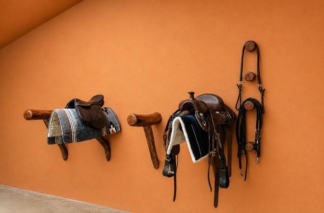 Premium equestrian tack displayed on handcrafted hardwood saddle racks inside The Tack Room at Vonfidel Ranch in Sri Lanka.
