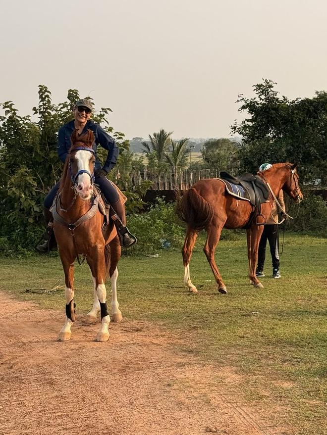 Guest on horseback at Vonfidel Ranch with saddled horses and ranch grounds in the background