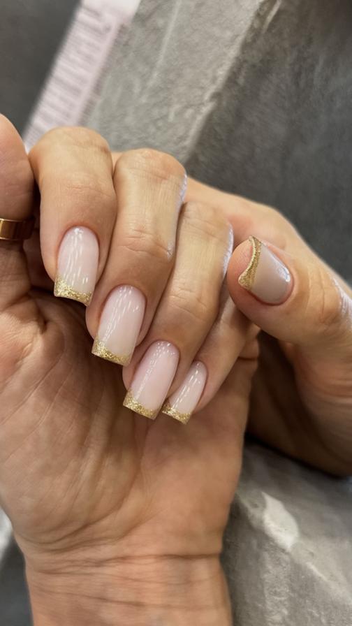 Nude manicure with gold glitter French tips